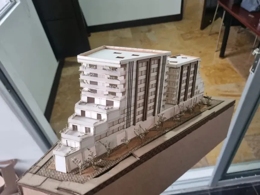 Maqueta del conjunto vista desde arriba: las dos torres, la plataforma comercial y el frente arbolado sobre la calle.